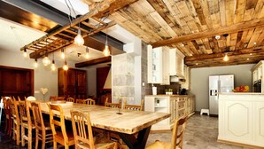 A spacious dining area with a large wooden table and chairs, a kitchen with white cabinets, and exposed wooden beams on the ceiling. - Magnificent Holiday Home in Baronville With Heated Pool & Billiards (Beauraing)