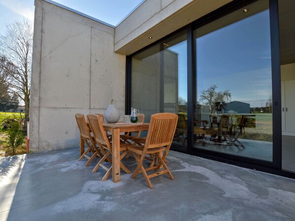 Un patio al aire libre con una mesa, sillas, un florero y una jarrón.