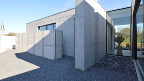 A modern building with a concrete facade, large windows, and a gravel driveway. - Modern Villa Stay in Dalhem (Dalhem)