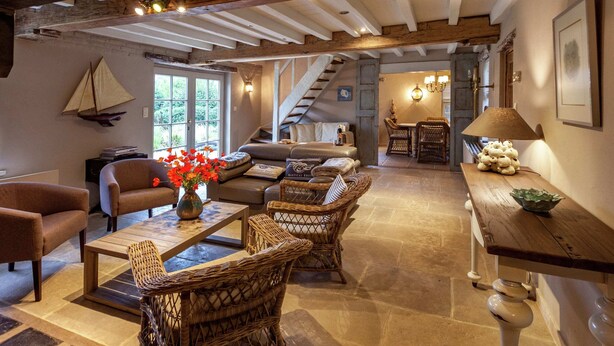 A rustic interior with a wooden ceiling, wicker furniture, a dining area, and a staircase. - Aesthetic Coastal Villa in Koksijde (Koksijde)