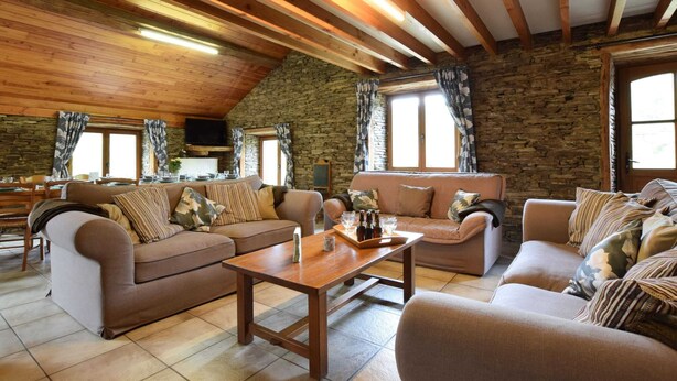 A cozy living room with wooden beams, stone walls, and two sofas with patterned cushions. - Lovely Holiday Home In Frahan With Terrace (Bouillon)