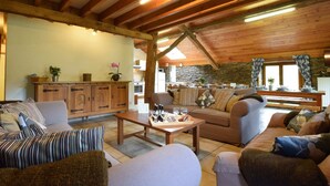 A cozy living room with wooden beams, a sofa, a coffee table, and a stone wall. - Lovely Holiday Home In Frahan With Terrace (Bouillon)