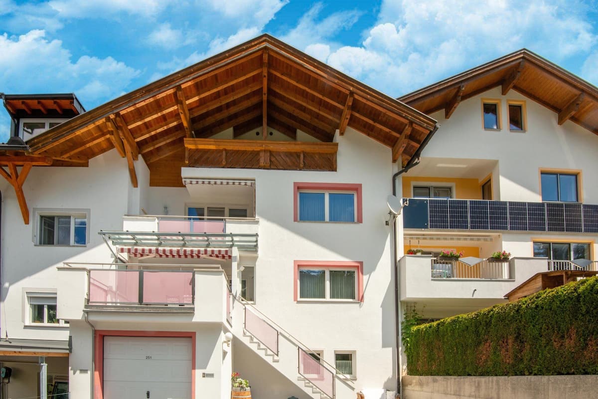 Un edificio de varios pisos con techo inclinado, balcones y garaje.