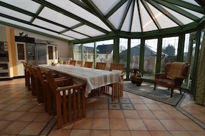 A conservatory with a dining table, chairs, and a kitchen area with cabinets and appliances. - Villa in Middelkerke Near the Beach (Middelkerke)
