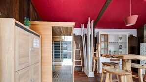 A wooden interior with a red ceiling, a glass door leading outside, and a wooden table with stools. - Splendid Villa in Middelkerke with Sauna, Hot Tub, Terrace (Middelkerke)