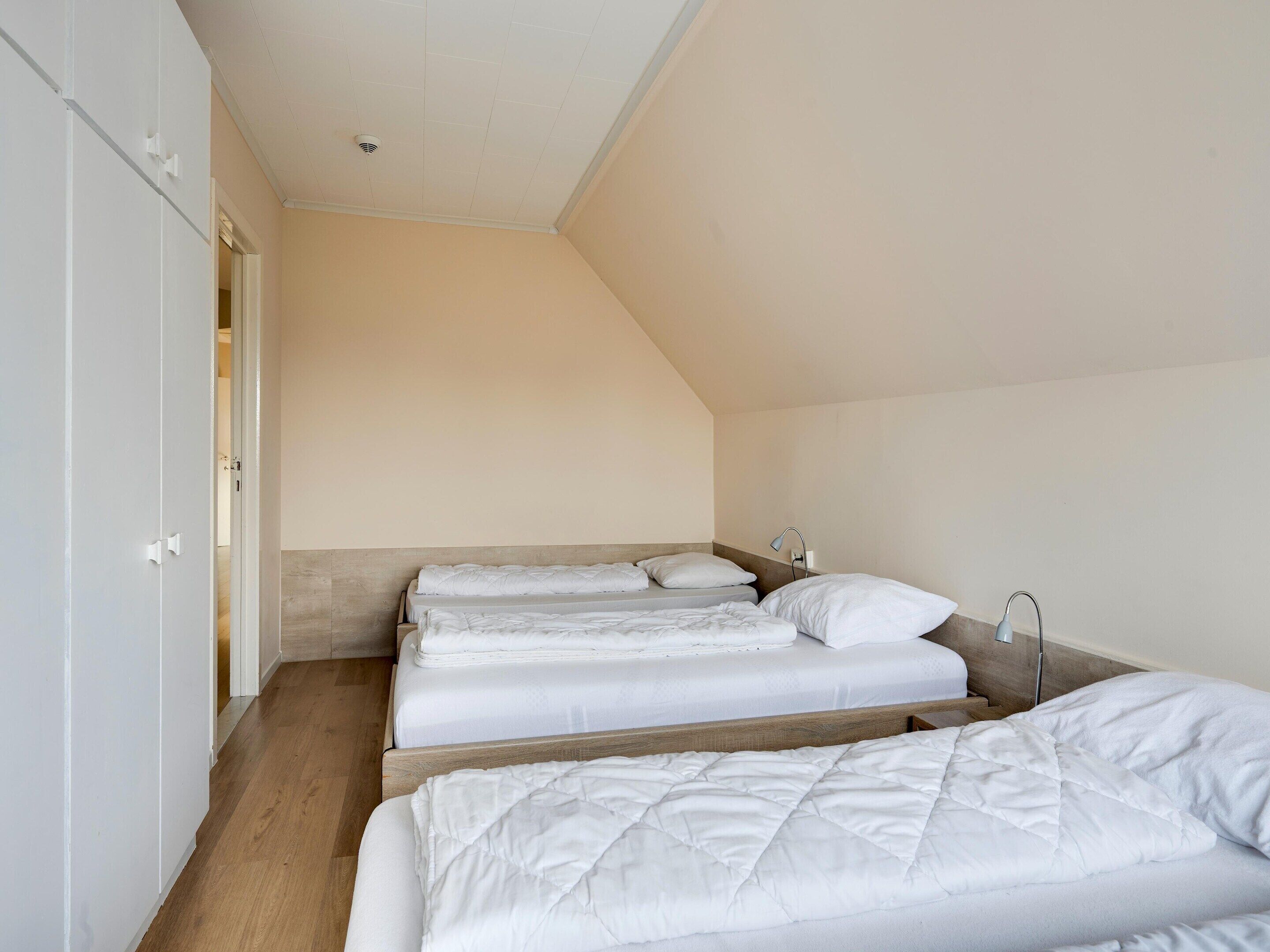 Une chambre avec deux lits, un plancher en bois et un plafond blanc.