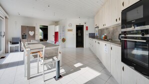 A modern kitchen with white cabinetry, a dining area with a table and chairs, and a Siemens oven. - Splendid Villa in Middelkerke with Sauna, Hot Tub, Terrace (Middelkerke)