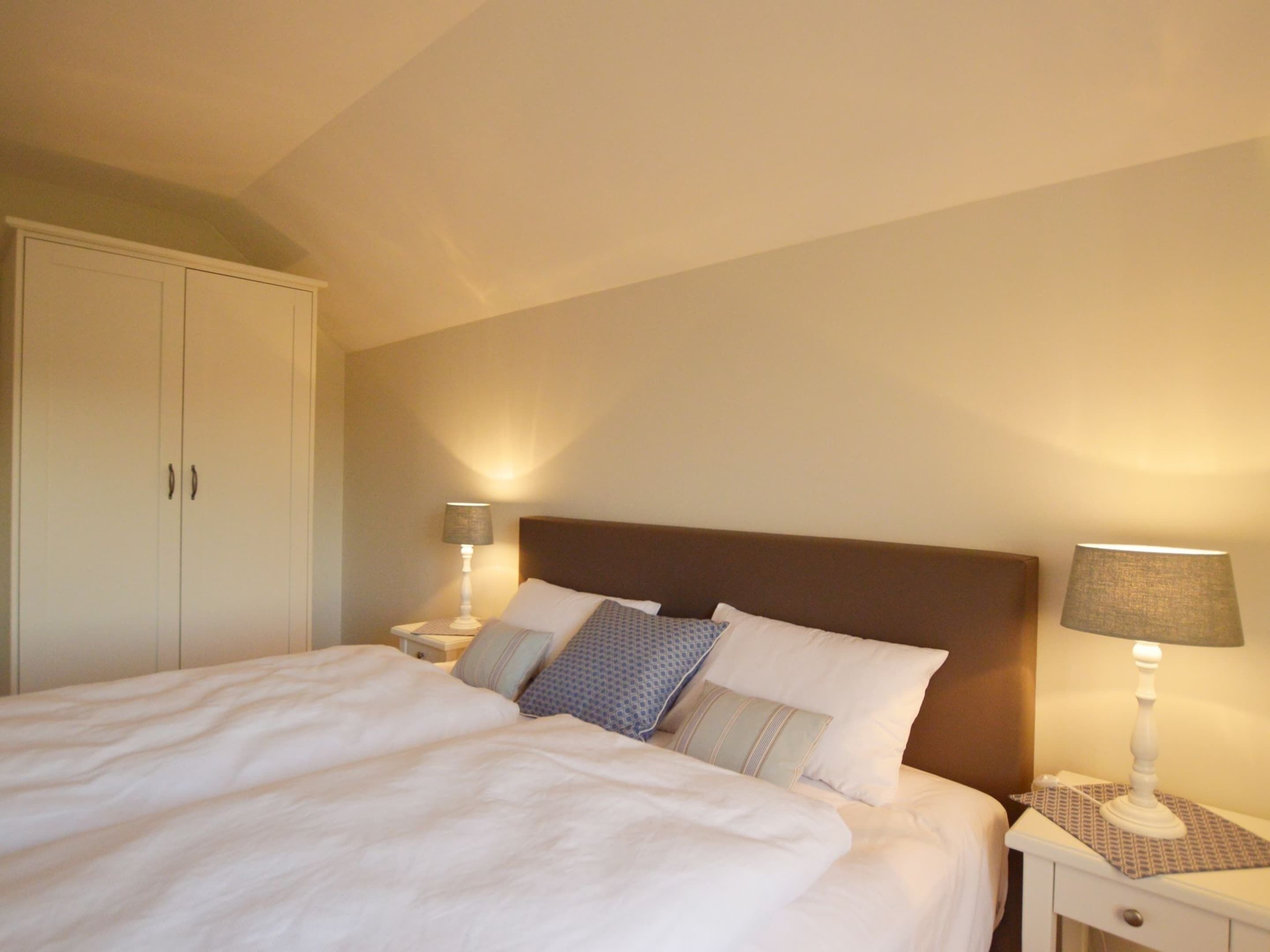 Ein Schlafzimmer mit einem Bett, zwei Nachttischen, einem Schrank und einem Kleiderschrank.