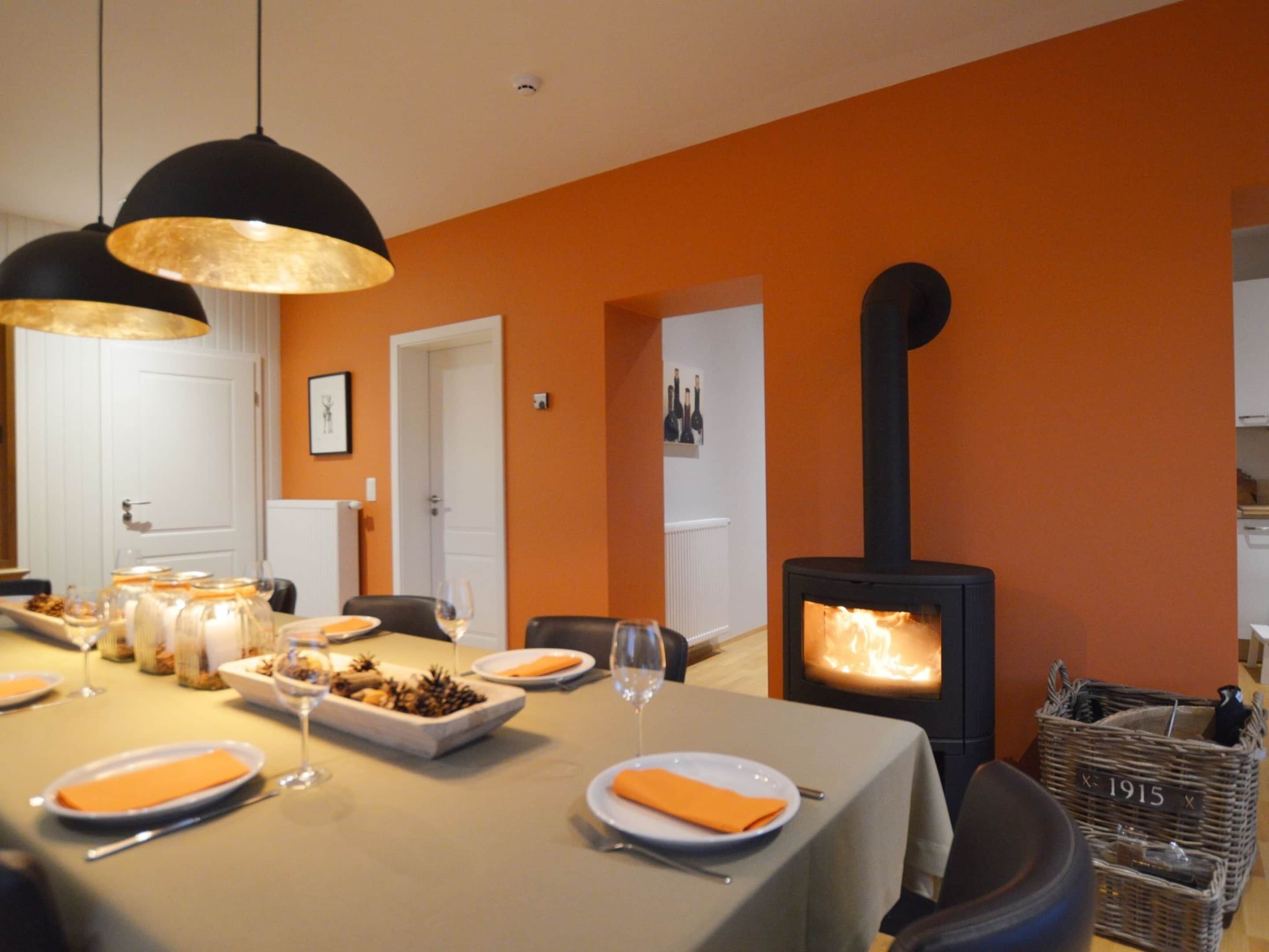 Uma sala de jantar com uma mesa posta para quatro pessoas, uma lareira e uma cesta de vime com a etiqueta '1915'.