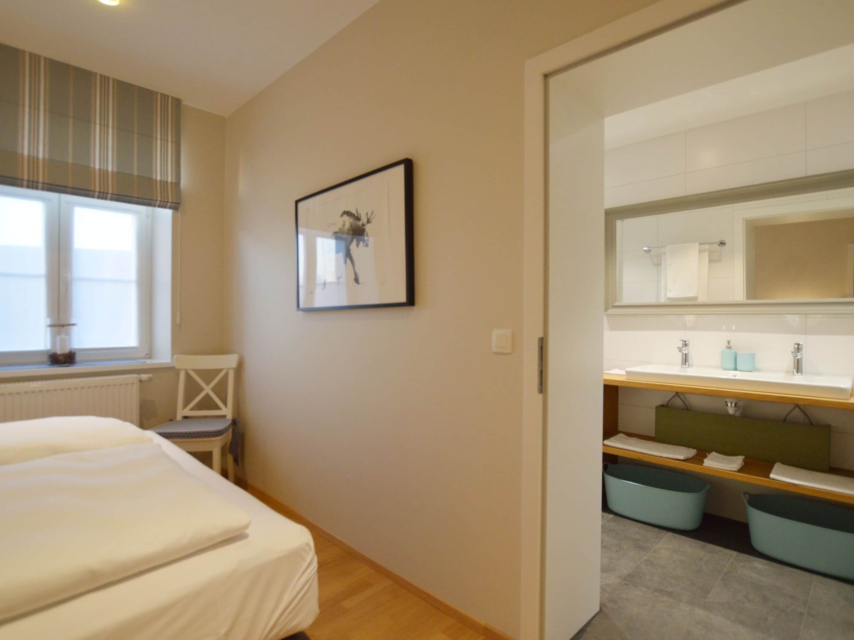 A bedroom with a bed, a window with blinds, a radiator, and a framed picture on the wall.