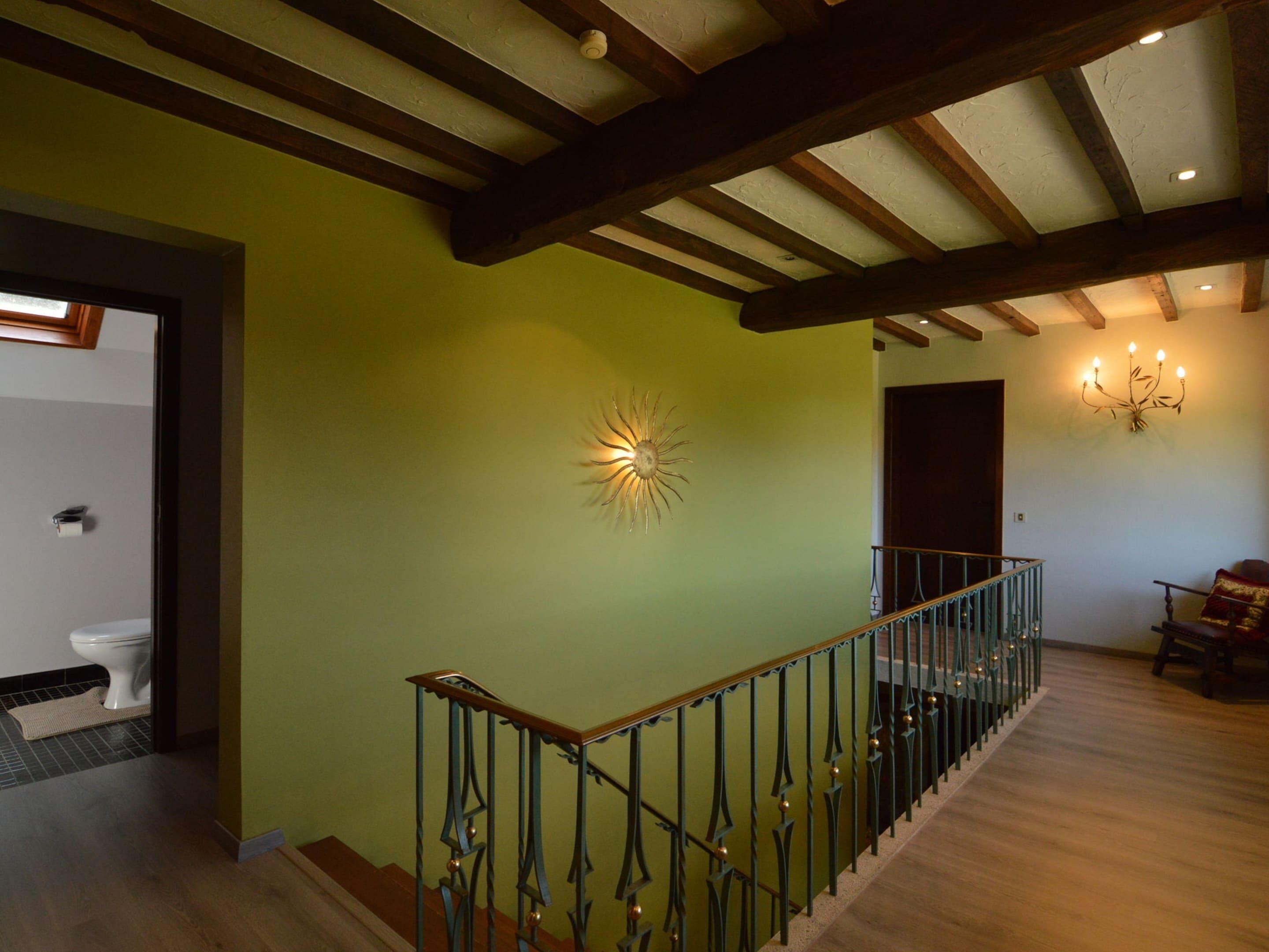 Un escalier avec une rampe en métal, un luminaire fixé au mur et une porte donnant sur une autre pièce.