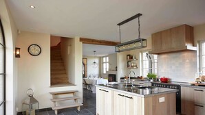 A modern kitchen with a central island, wooden cabinets, and a large window. - Country House in Sint Laureins Near Het Zwin (Sint-Laureins)