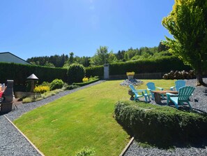 A well-maintained backyard with a lawn, a seating area with chairs, a small table, and a decorative stone feature.