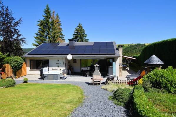 A house with a solar panel roof, a barbecue area, and a well-maintained garden.