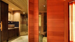 Une salle de bain moderne avec un meuble-lavabo en bois, un espace douche et une porte en verre donnant sur une chambre.
