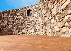 Un mur de pierre doté d’une ouverture circulaire.