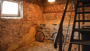 A room with a brick wall, a window, a bicycle, and a metal ladder. - A Cosy Vintage Loft to Discover, Ideal for Exploring the Region by Bike (Clavier)
