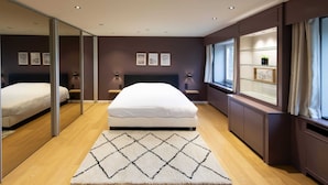 A modern bedroom with a large bed, a glass partition, and a view of a cityscape. - Modern House With Private Pool in Aubel (Aubel)