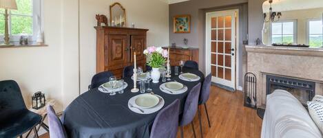 A dining room with a table set for six, a fireplace, and a large mirror above the mantel.