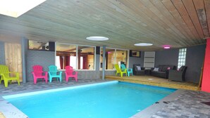 A swimming pool with colorful chairs and a seating area with sofas. - Superb House for Family Group with Swimming Pool, Sauna, Hot Tub, Billiards (Trooz)