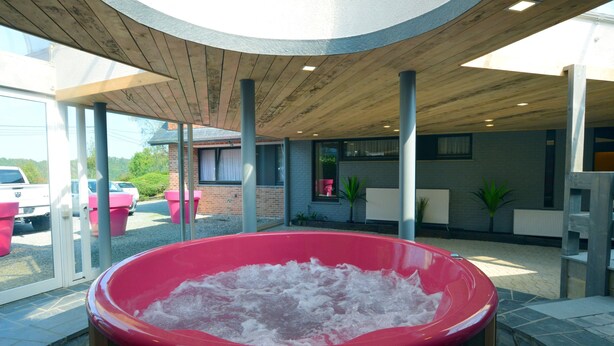 A hot tub in a covered outdoor area with a view of parked cars and a building in the background. - Superb House for Family Group with Swimming Pool, Sauna, Hot Tub, Billiards (Trooz)