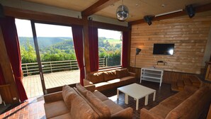A spacious living room with a large sofa, a coffee table, and a TV mounted on a wooden wall. - Superb House for Family Group with Swimming Pool, Sauna, Hot Tub, Billiards (Trooz)