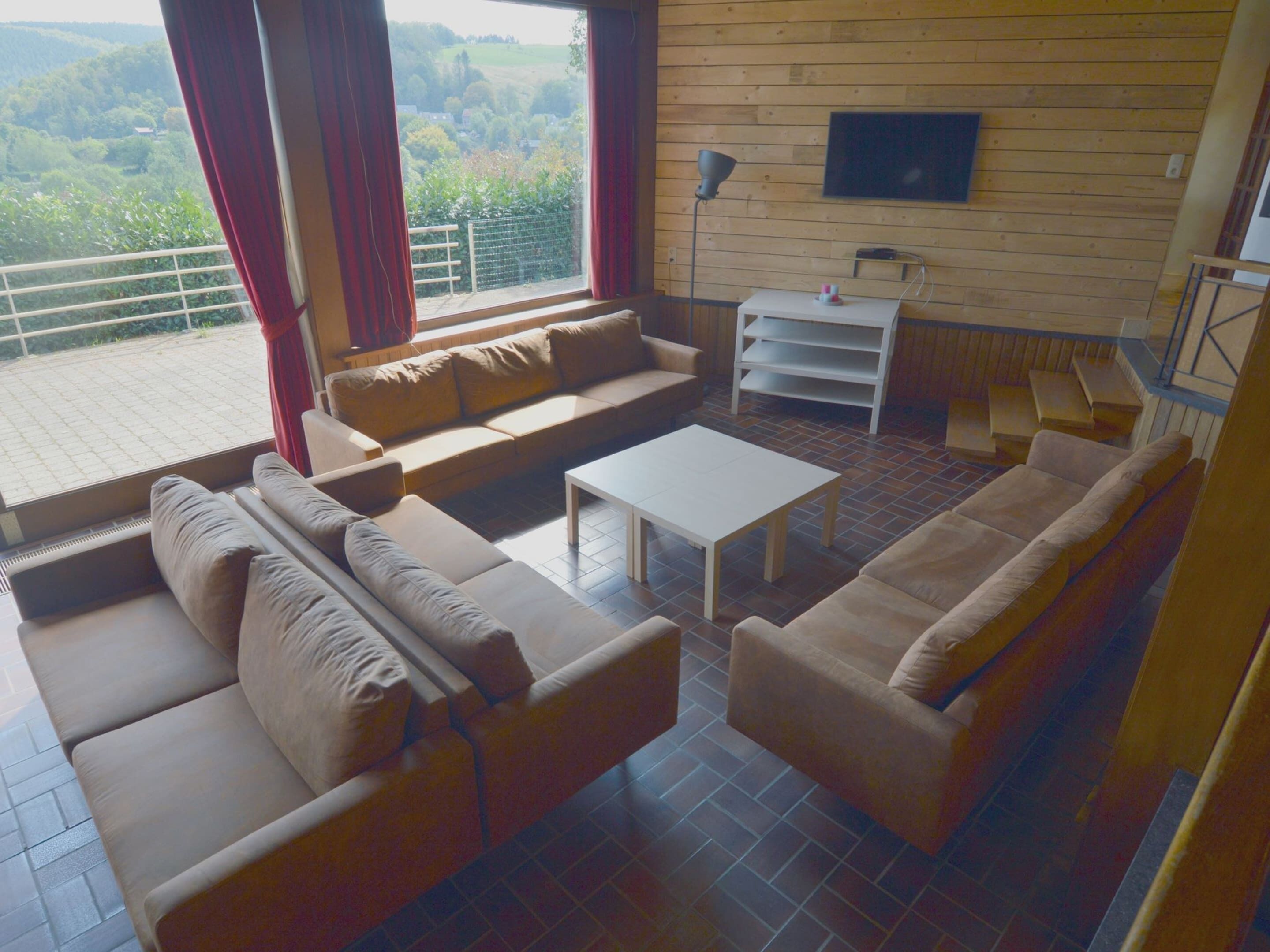 A modern living room with a sofa set, a coffee table, and a TV mounted on the wall.