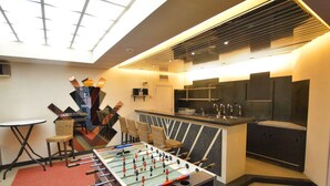 A room with a foosball table, a small bar area, and a seating area with chairs and a table. - Superb House for Family Group with Swimming Pool, Sauna, Hot Tub, Billiards (Trooz)