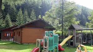 A wooden cabin with a slide and play structures in a forested area. - Chalet in Valais Near Ski Lift & Saas Valley (Saas-Balen)