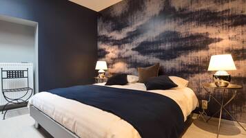 Une chambre moderne avec un grand lit, deux tables de chevet avec des lampes, un radiateur et un fauteuil.