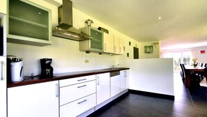 Une cuisine moderne avec des armoires blanches, une hotte de cuisinière en acier inoxydable et un four encastré.