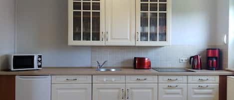 Una cocina con armarios blancos, microondas, tostadora y cafetera.