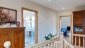 Uma sala de estar ampla com escada, armários de madeira e um quadro na parede.