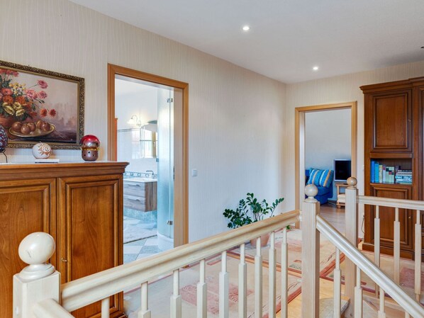 A spacious living area with a staircase, wooden cabinets, and a painting on the wall. - Apartment in Kuhlungsborn Near Sandy Beach (Kuehlungsborn)
