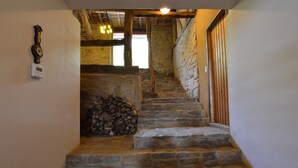 A stone staircase leading to a wooden door, with a stack of firewood at the bottom and a wall-mounted clock. - Holiday Home in Odeigne With Sauna (Manhay)