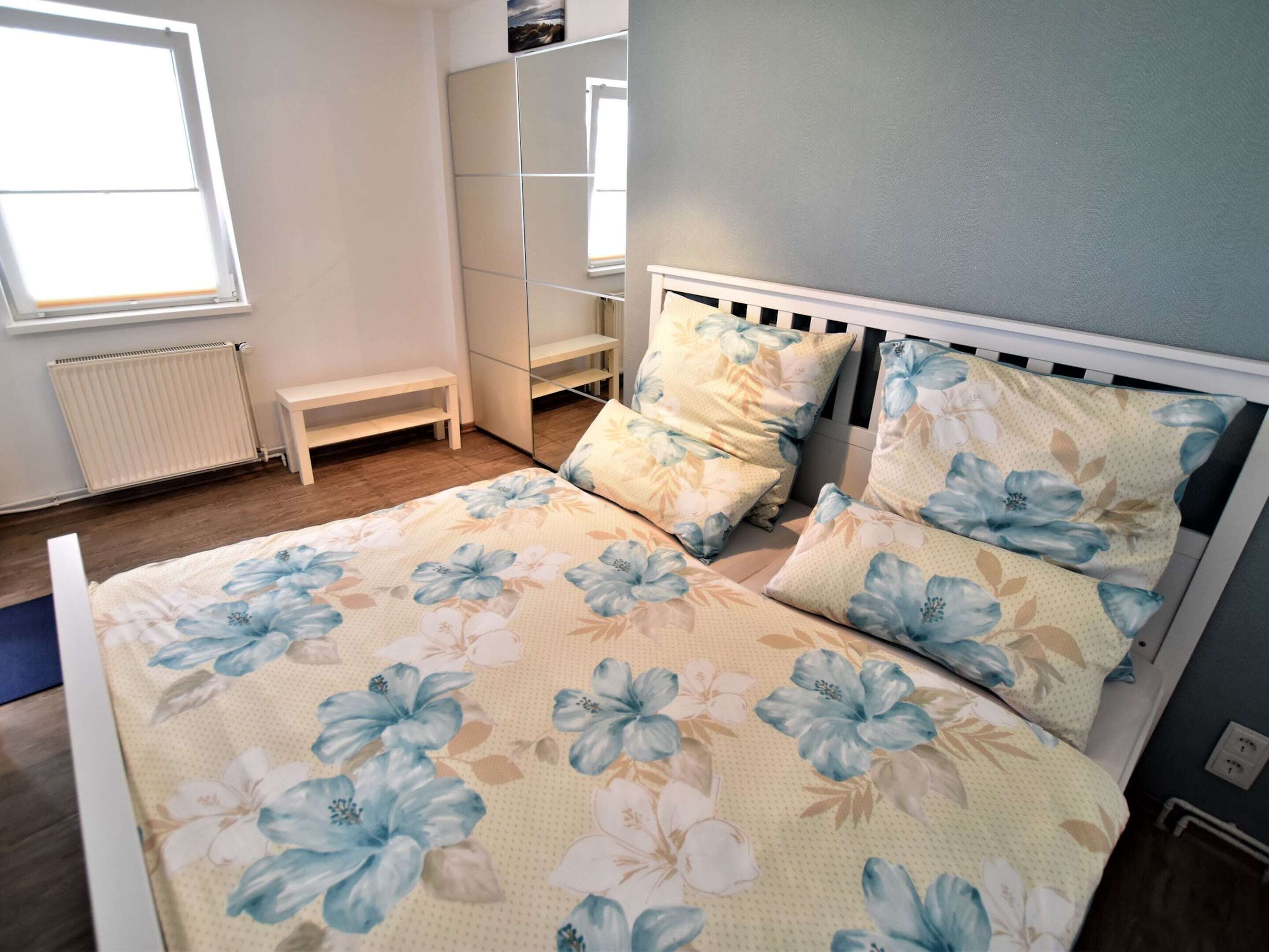 A bedroom with a bed, a bench, a wardrobe, and a window.