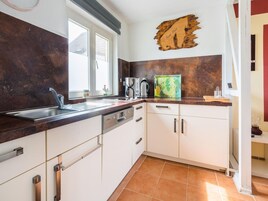 A modern kitchen with a stainless steel sink, white cabinets, and a coffee maker.