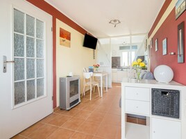 Una cocina moderna con comedor, televisor montado en la pared y un refrigerador pequeño.