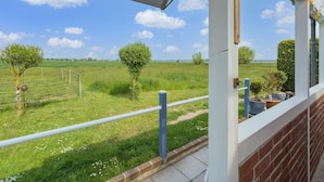 Un balcon donnant sur un champ verdoyant et des arbres.