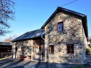 A stone building with a wooden door and windows, a gravel driveway, and a red table and chairs outside. - Cozy, Authentic and Quiet House (Vielsalm)