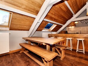 A cozy kitchen with a wooden table and bench, a skylight, and a tiled backsplash. - Cozy, Authentic and Quiet House (Vielsalm)