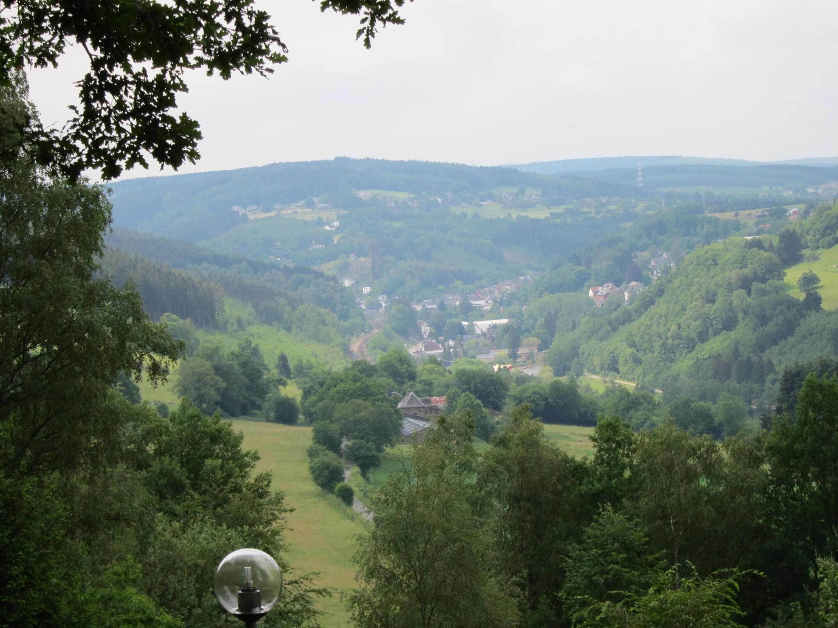 A panoramic view of a lush valley with dense greenery and scattered buildings.