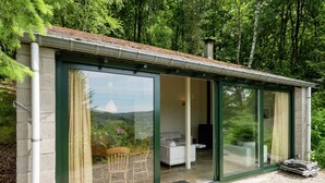 A modern house with large sliding glass doors, a stone exterior, and a view of a forested landscape. - Great Spacious Holiday Home in a Tranquil Holiday (Stavelot)