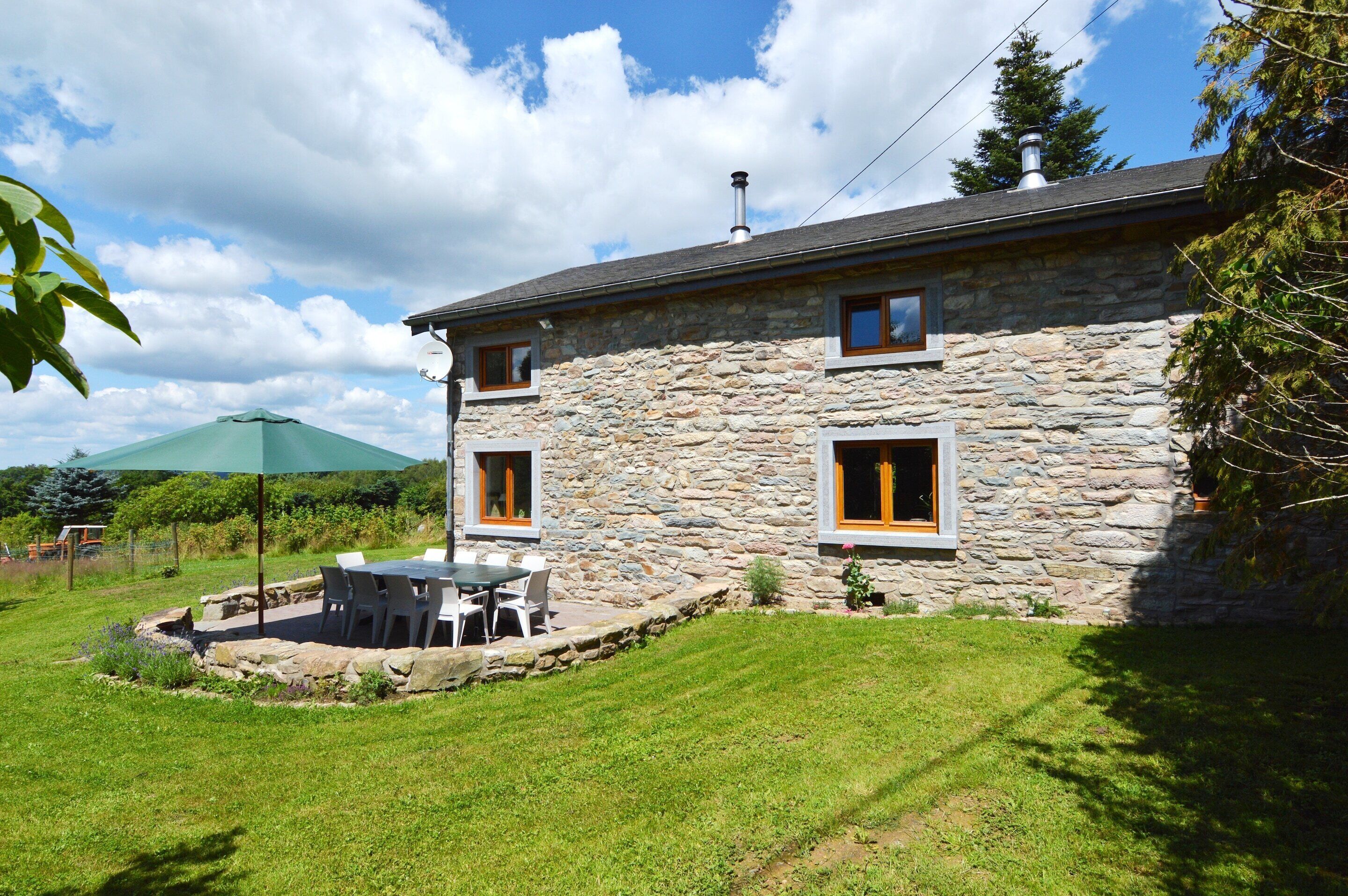 A stone building with a patio, a table, and chairs.