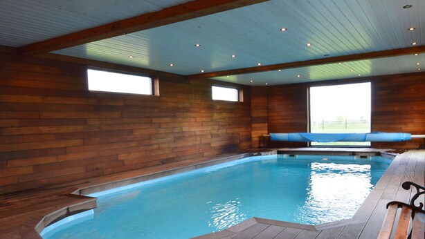 A large indoor swimming pool with wooden walls and a wooden deck. - Luxury Villa in Sourbrodt (Waimes)