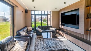 A modern living room with leather sofas, a large flat-screen TV, and a patterned rug. - Luxury Villa in Sourbrodt (Waimes)