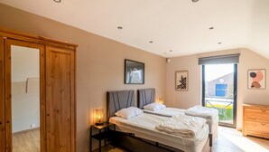 A bedroom with a large bed, a wardrobe, a bedside table with a lamp, and a window with a view of the outside. - Luxury Villa in Sourbrodt (Waimes)