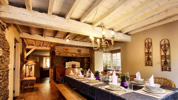 A long dining table set for a meal in a rustic room with exposed wooden beams and stone walls. - Ardennic Farmhouse for Groups (Vielsalm)