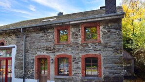 A stone building with multiple windows and a red door. - Ardennic Farmhouse for Groups (Vielsalm)