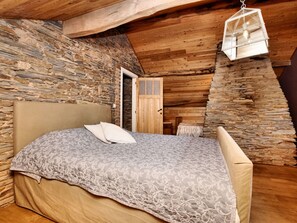 A cozy bedroom with a stone wall, a wooden ceiling, and a hanging light fixture. - Ardennic Farmhouse for Groups (Vielsalm)